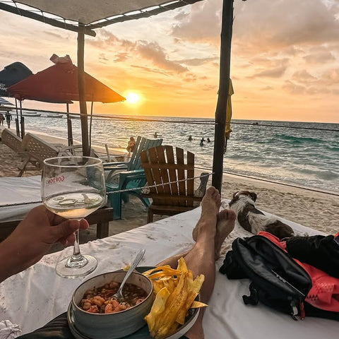 Person enjoying a sunset at the beach with food and a glass of wine in playa blanca