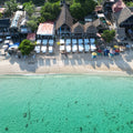 Aerial view of a beachfront with lounge chairs and umbrellas by a clear blue sea.