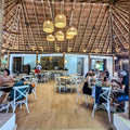 People dining in Pedro Majagua restaurant with thatched ceiling and wooden floor.